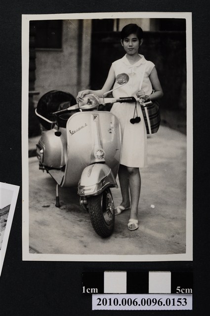身穿有領無袖連身洋裝女子與偉士牌摩托車合影之照片 (共2張)