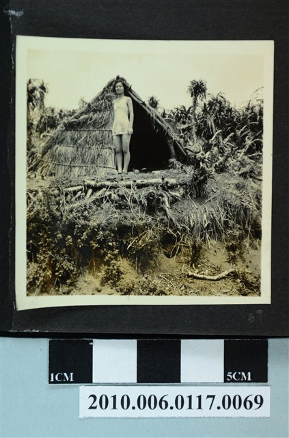 一女子站立於茅草屋前獨影之照片 (共1張)