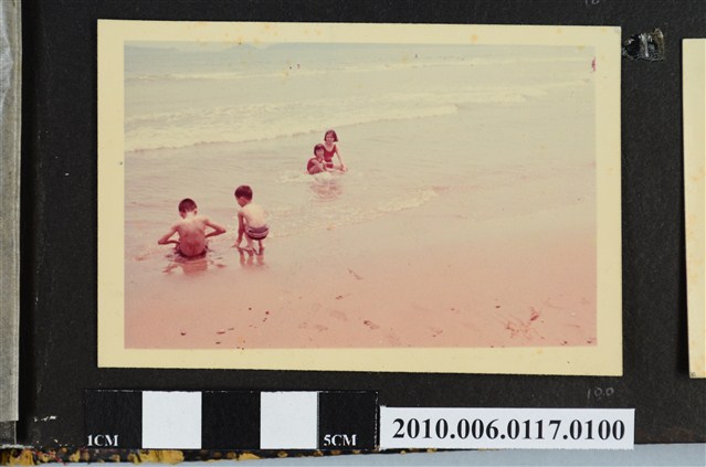 一女子與三位孩童坐在海邊戲水的照片 (共1張)