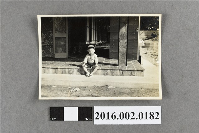 一位坐在房舍外廊地板的小男孩 (共2張)