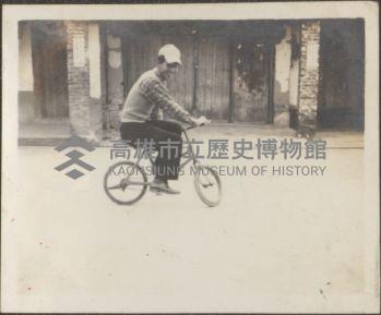 日光照相館創辦人張仁葵於民居前騎小腳踏車藏品圖，第1張